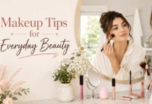 Young woman applying natural everyday makeup at a vanity with concealer, mascara, blush, and beauty essentials in a bright, elegant setting.