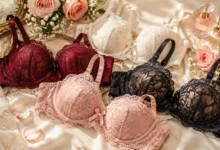 Elegant lacy bras collection featuring romantic floral lace designs arranged on luxurious satin fabric with soft rose accents.