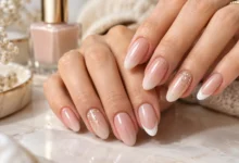 Elegant nude nails featuring French tips, soft pink shades, and delicate gold glitter accents