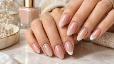 Elegant nude nails featuring French tips, soft pink shades, and delicate gold glitter accents