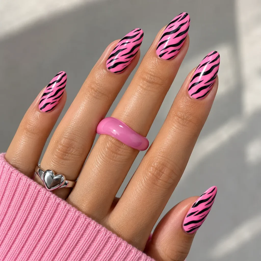 Pink Y2K zebra print nails featuring bright pink polish, bold black stripes, and a glossy almond-shaped manicure.